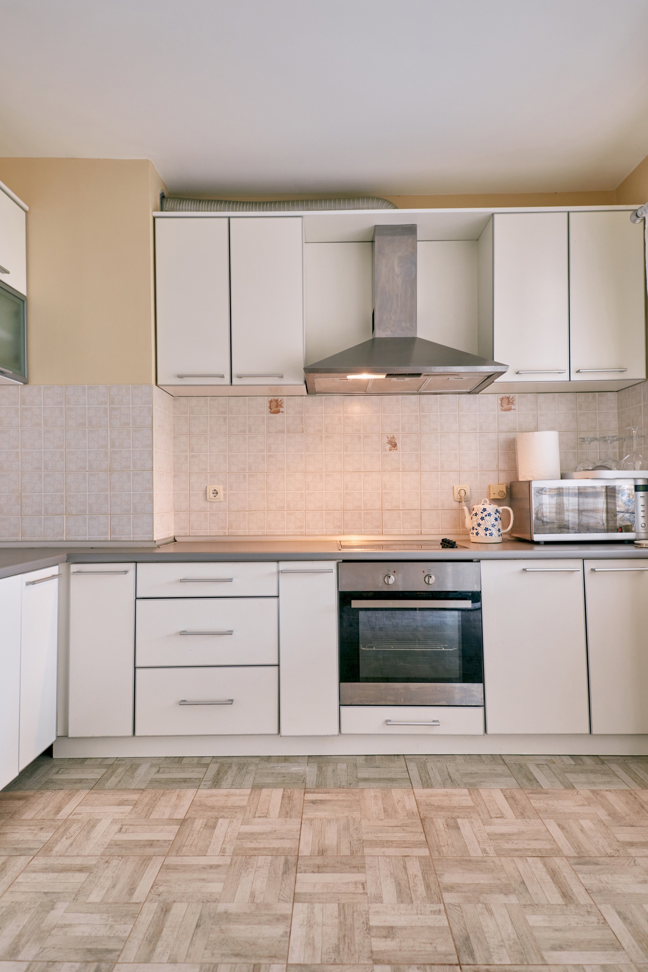 Minimalist kitchen with hood over stove and cabinets